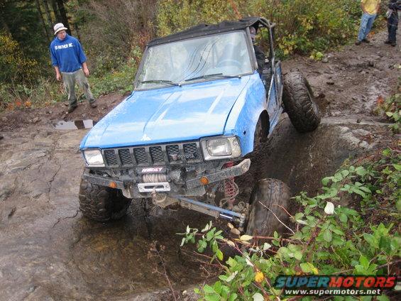 Blue off-road vehicle with a winch on the front bumper, stuck on a rocky trail