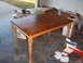 1988 Ford Bronco - A wooden dining table sits in a garage, with a model airplane and various boxes in the background.