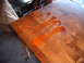 1988 Ford Bronco - Orange liquid is poured onto a wooden table surface, with a table leg visible at the bottom left.