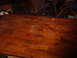 1988 Ford Bronco - A wooden table with visible water damage and scratches is shown, with chairs in the background.