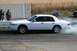1997 Mercury Grand Marquis - A white sedan spins its tires, creating smoke on the drag strip.