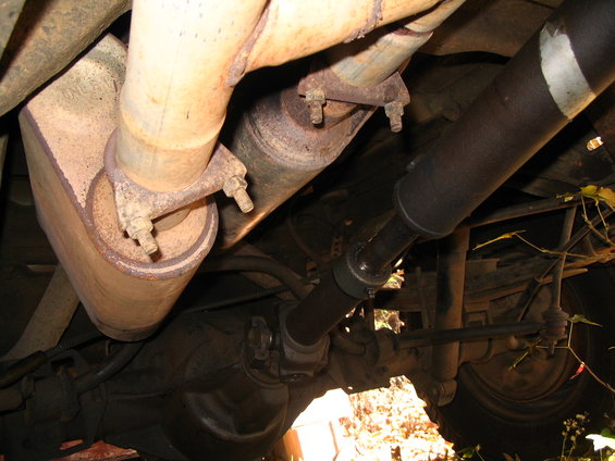 Undercarriage view showing exhaust pipes, muffler, driveshaft, and rear axle components