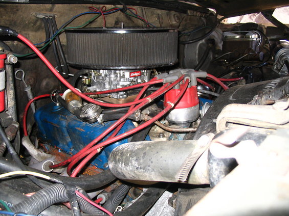 Engine bay detail showing carburetor, distributor, and spark plug wires