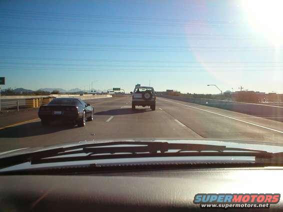 White SUV with a spare tire on the rear door, driving on a highway