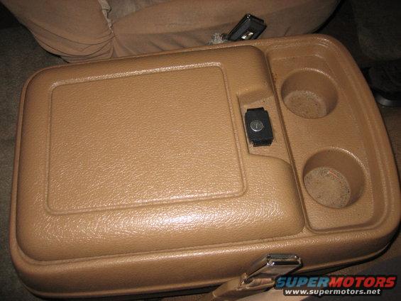 Tan center console with two cup holders and a lock, interior view