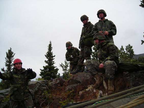 Soldiers in camouflage on a rocky hill under a cloudy sky
