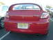 2005 Dodge SRT-4 - This red Dodge Neon SRT-4 is parked in a lot, showing its rear end and a large spoiler.