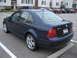 2002 Volkswagen Jetta - This dark blue sedan is parked in a lot with apartment buildings in the background.