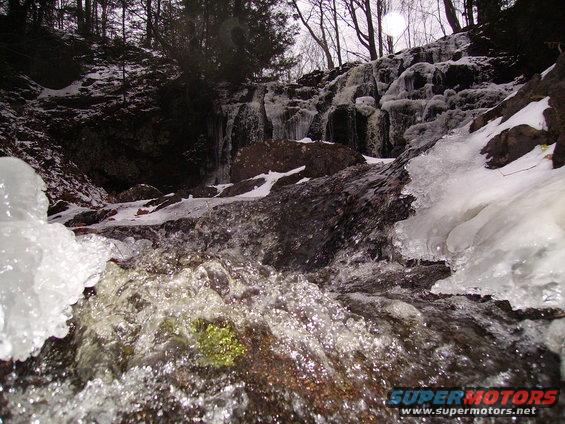 Frozen waterfall with ice and snow on rocks and trees