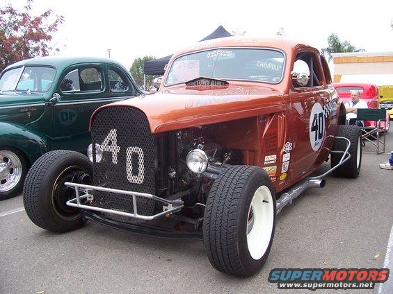Orange hot rod with number 40 on the grille and side, parked next to a green classic car