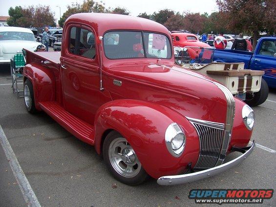 Red 1940s pickup truck with chrome grille and headlights, parked outdoors