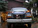 1995 Ford F-250 - A blue pickup truck is parked in front of a garage, equipped with a plow mount and auxiliary lights.