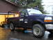 1995 Ford F-250 - A dark blue Ford F-250 truck is parked outside a garage, with a black sports car visible inside.