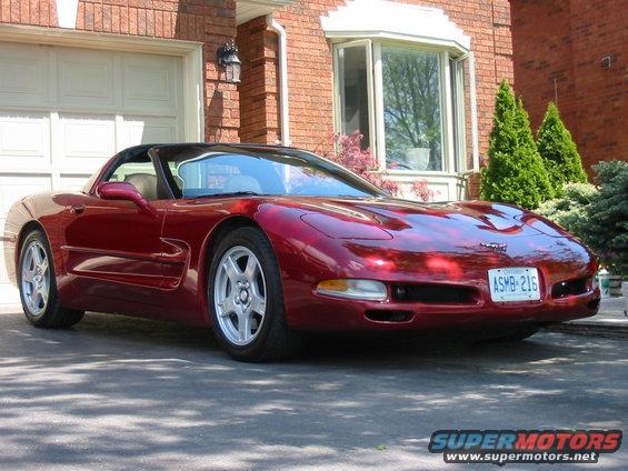 Red convertible sports car parked in front of a brick house
