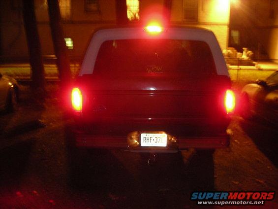 Dark red SUV's rear end with white roof, illuminated taillights, and license plate RHF-370