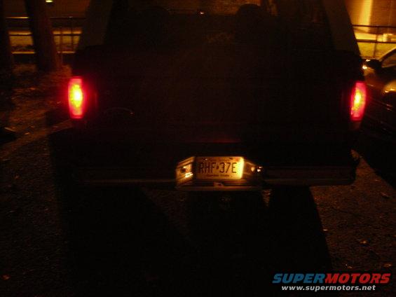 rear of a dark pickup truck with license plate RHF 37E illuminated