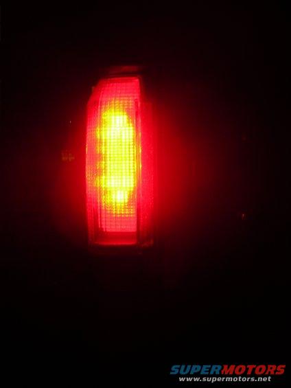Close-up of a red vehicle tail light with yellow LEDs illuminated