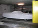 1972 Ford Ranchero - A vehicle is covered by a sheet in a dimly lit garage, with a yellow pillar to the right.