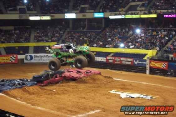 Monster truck airborne over crushed cars in an arena