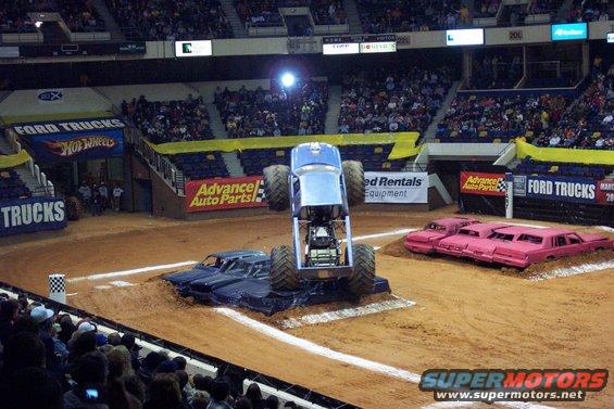 Monster truck airborne over crushed cars in arena