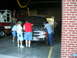1989 Ford Bronco - Three men examine the engine of a truck parked inside a garage next to a fire truck.