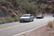 2006 Mazda RX-8 - A silver sedan leads a gray coupe on a winding road through a desert landscape, with a Supermotors watermark visible.