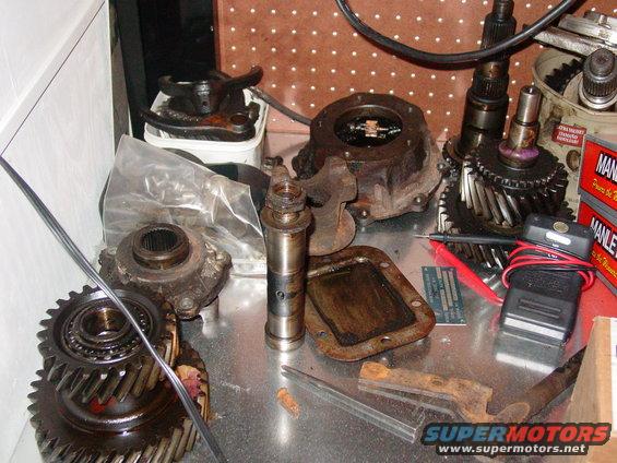 Various greasy transmission gears and components laid out on a metal surface