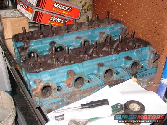 Pair of blue engine cylinder heads with tools and Manley boxes