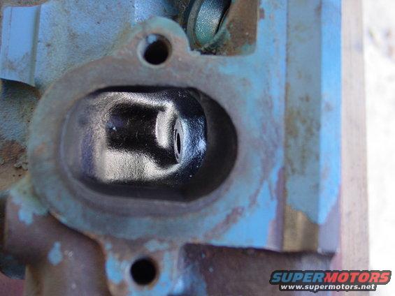 Close-up of a blue and rusty engine cylinder head with a dark intake port
