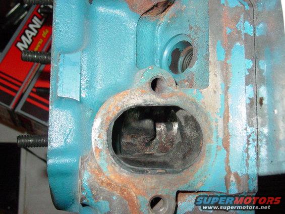 Close-up of a teal-painted engine cylinder head with rust and bolt holes