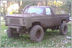 Mud-covered pickup truck with large tires and snorkel intake