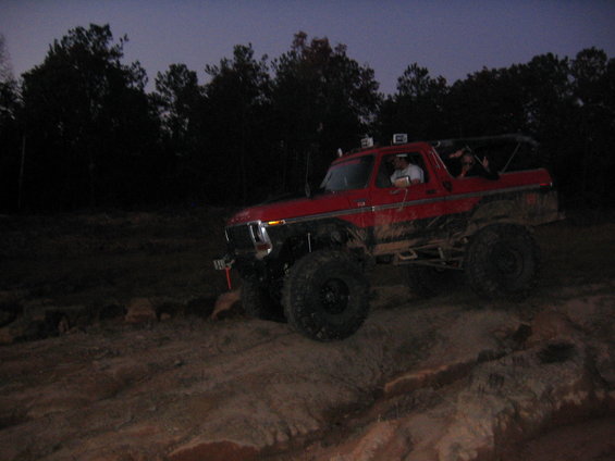 red 1979 Ford Bronco driving off-road at dusk