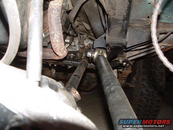 Undercarriage of a green vehicle with visible suspension components, exhaust pipe, and tire