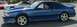1988 Ford Mustang - A blue coupe with a spoiler is parked next to other vehicles.