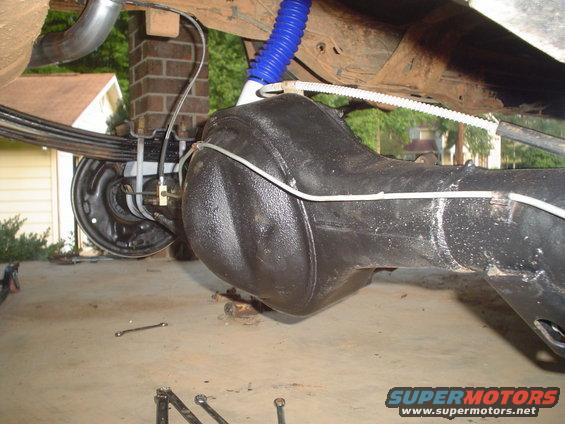 Close-up of a vehicle's rear axle and leaf spring suspension, with a blue shock absorber visible
