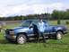 1995 GMC Sierra 1500 - A blue 1995 GMC Sierra 1500 pickup truck is parked on grass with a person standing next to it.