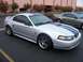 2002 Ford Mustang - A silver 2002 Ford Mustang with blue racing stripes is parked in a lot, with another Mustang visible in the background.