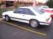 2002 Ford Mustang - A white coupe with distinctive rear window louvers is parked in a lot next to other vehicles.