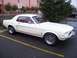2002 Ford Mustang - A classic white 1967 Ford Mustang coupe is parked in a lot, red racing stripes along its side and chrome wheels.