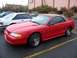 2002 Ford Mustang - Red convertible Mustang parked in a lot next to a white coupe.