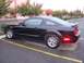 2002 Ford Mustang - This black Ford Mustang is parked in a lot, showing its side profile and rear spoiler.