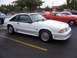 2002 Ford Mustang - A white coupe, likely a 1987 Ford Mustang GT, is parked in a lot next to a red classic car.