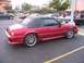 2002 Ford Mustang - A red convertible Mustang is parked in a lot, with other vehicles visible in the background.