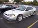 2002 Ford Mustang - A silver 2002 Ford Mustang coupe is parked in a lot, with another classic Mustang visible behind it.