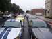2002 Ford Mustang - A line of Ford Mustangs, including a silver one with blue stripes, are parked on a street.