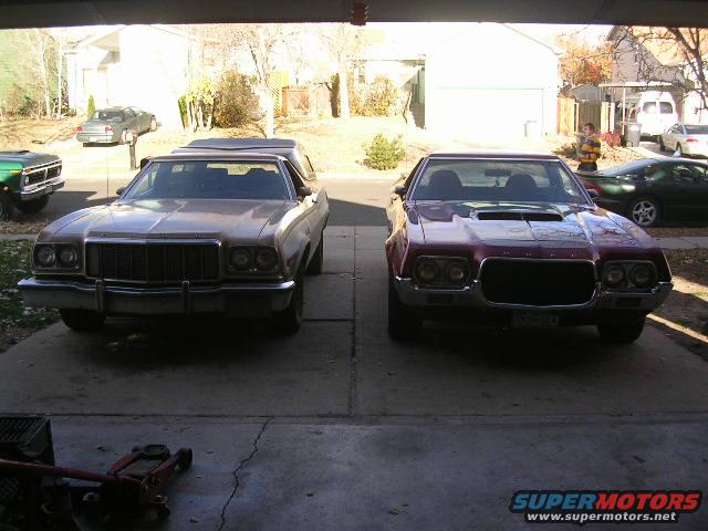Two Ford Rancheros parked front-end out, one tan and one maroon. The tan one has a large grille and quad headlights. The maroon one has a hood scoop