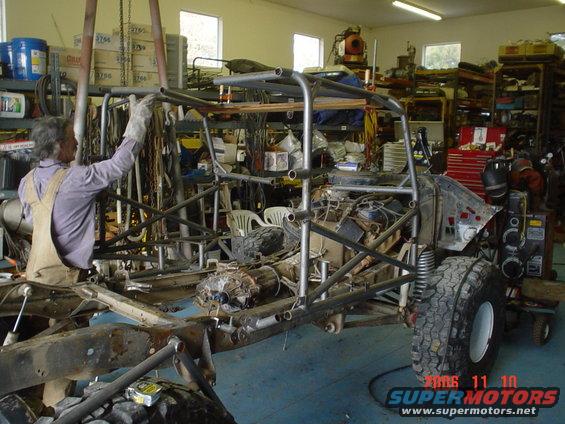 Man working on custom buggy frame in garage with tools and parts around