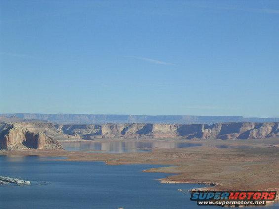 Lake Powell with layered rock formations under a clear blue sky