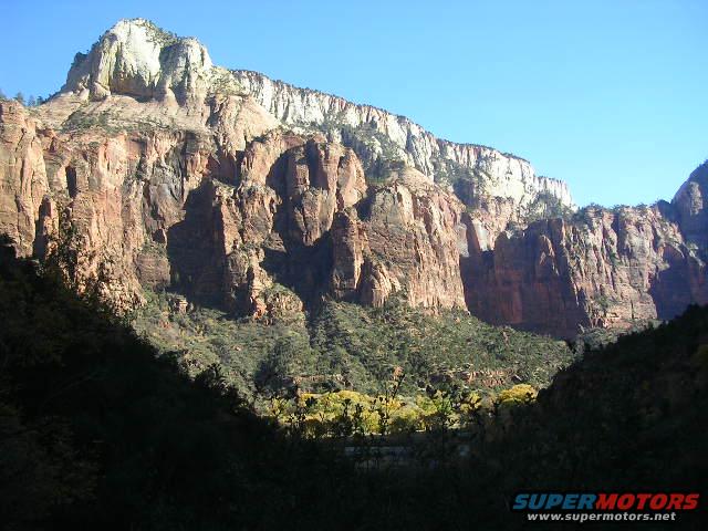 Mountain cliffs and trees under a clear blue sky
