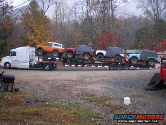 Orange 1969 Ford Bronco and other SUVs on a trailer